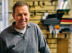 Smiling older man in a gray shirt indoors.