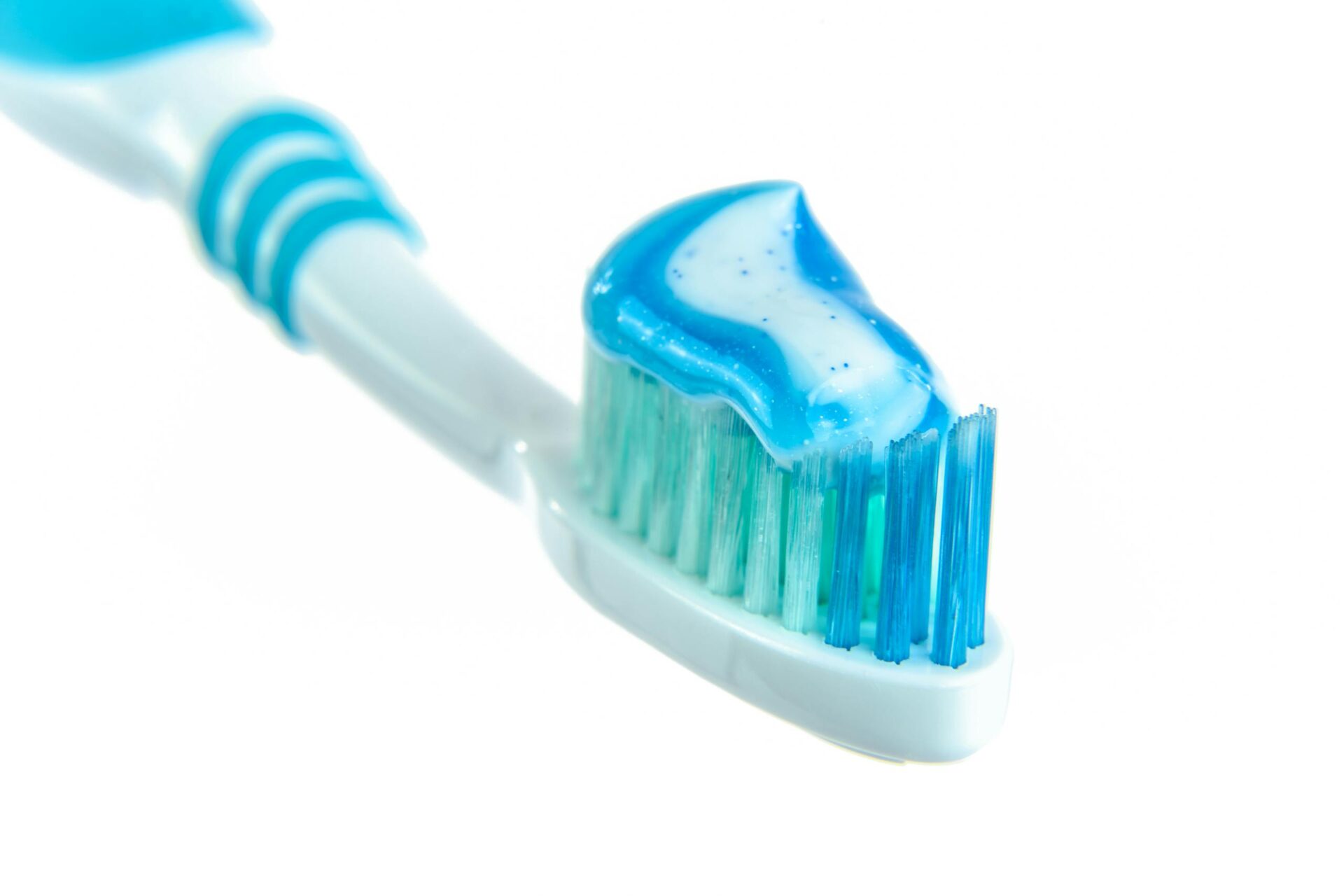 Close-up of a toothbrush head with blue toothpaste on the bristles.
