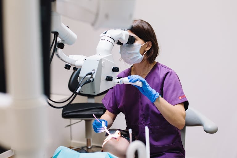 Dentist using a dental microscope while examining a patient in a clinic.