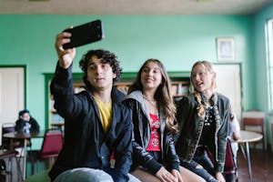 Three teenagers taking a selfie together indoors.