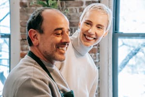 Smiling man and woman indoors near large windows