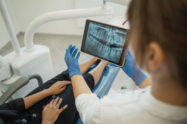 Dentist showing a dental x-ray on a tablet to a patient in a dental chair.
